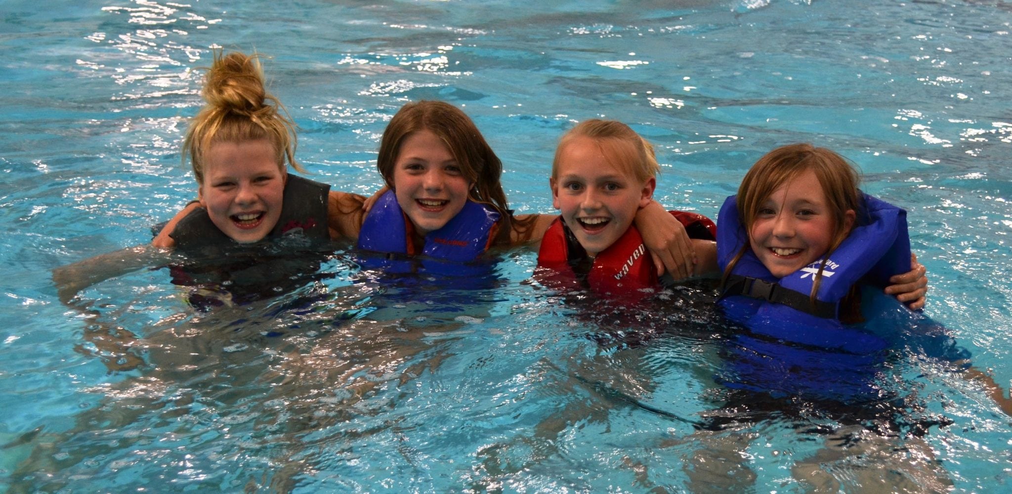 four young girls pose in the water for a picture