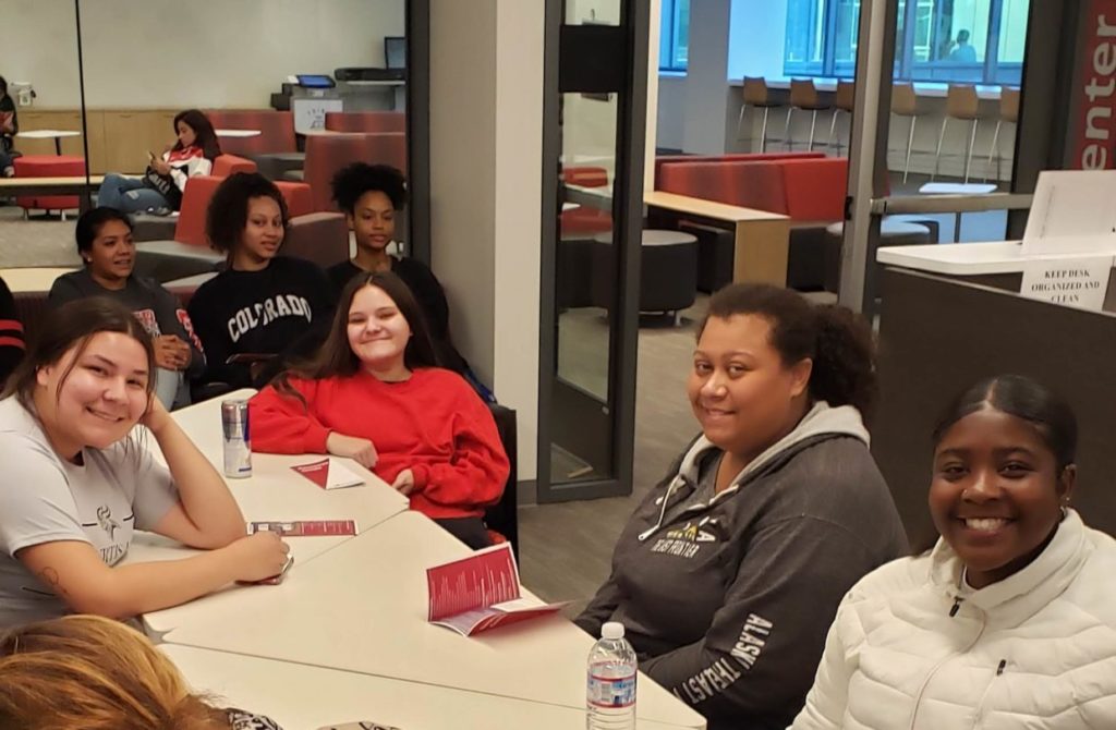 students looking at camera while sitting at table