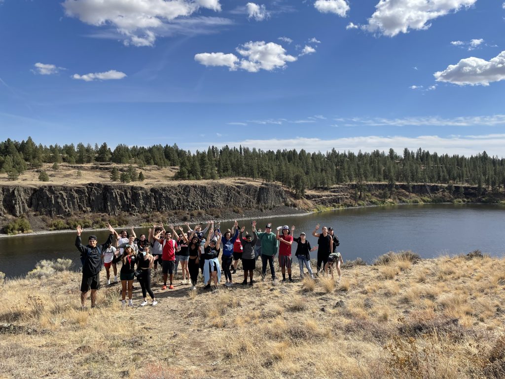 group of people posing in front of lake