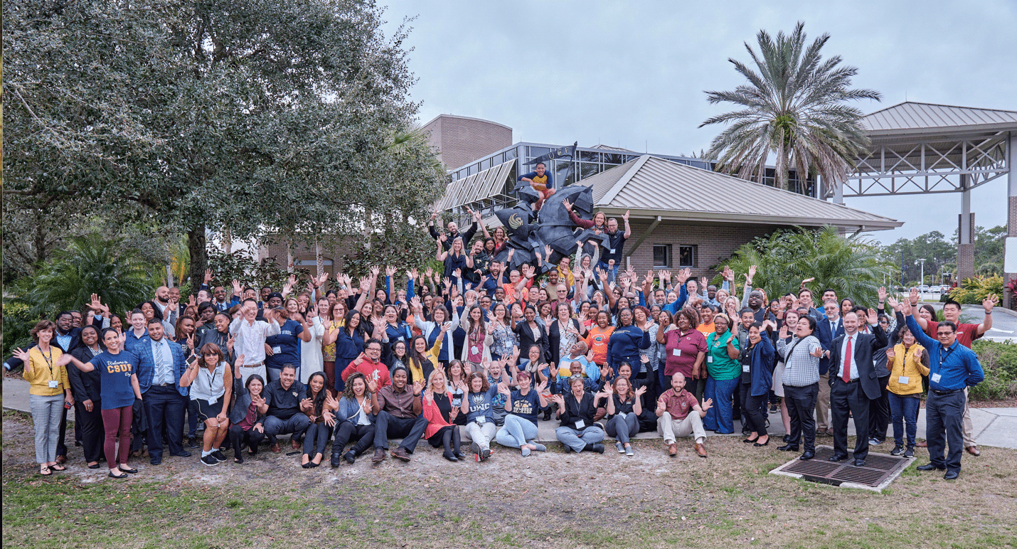 McNair Staff from around the country gather in Florida to talk about best practices - large group photo in front of statue and palm trees