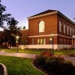 A photo of Hargreaves Hall in the evening. The building is made with red bricks and surrounded by grass.